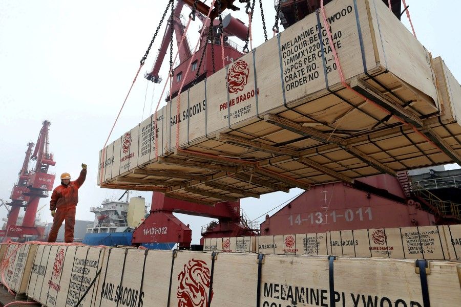 A worker gestures as a crane lifts goods for export onto a cargo vessel at a port in Lianyungang, Jiangsu province, China, 13 February 2019. (Stringer/REUTERS)