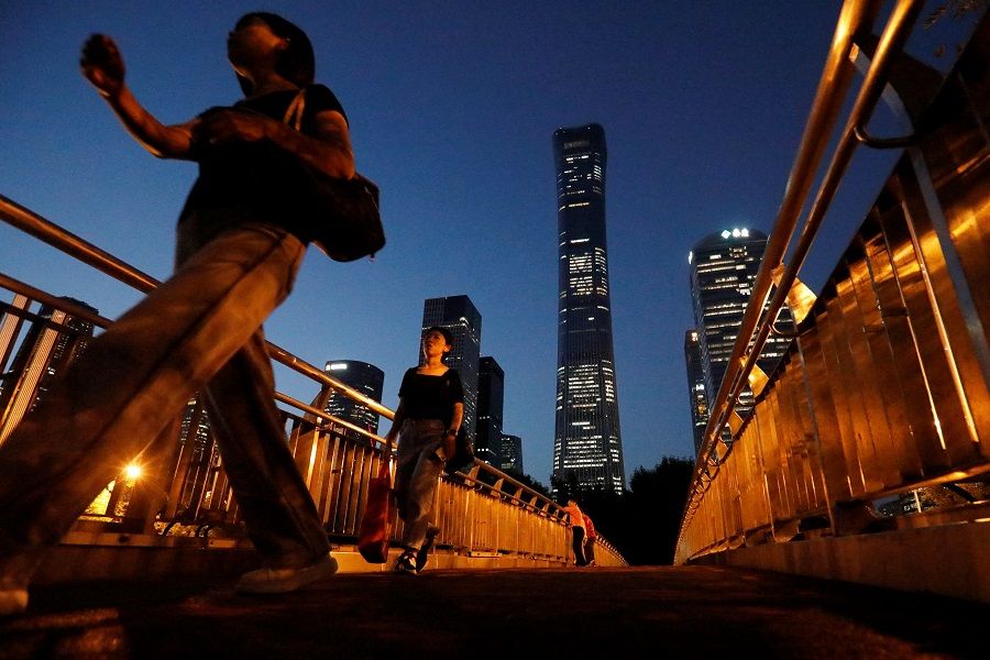 Pedestrians walk on an overpass near skyscrapers in the central business district in Beijing, China, on 21 August 2023. (Florence Lo/Reuters)