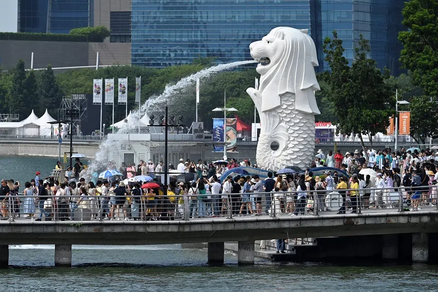 People gather next to the Merlion statue at the Marina Bay Waterfront Promenade in Singapore on 7 August 2024.