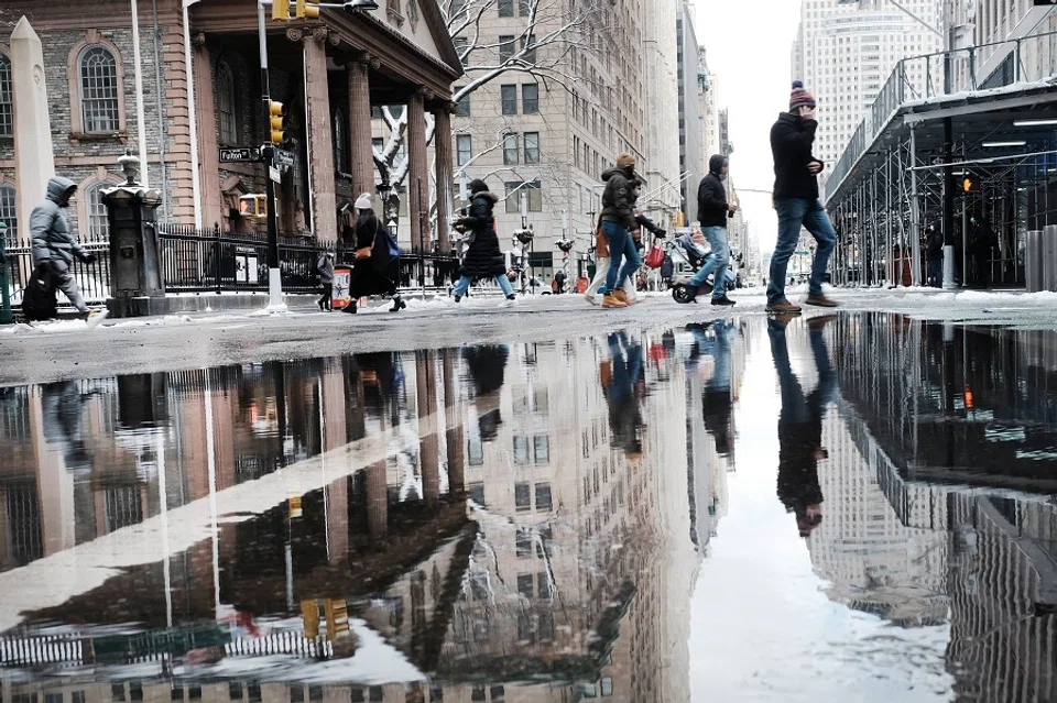 People walk through wet streets after a morning snow storm in Manhattan on 7 January 2022 in New York City, US. (Spencer Platt/Getty Images/AFP)