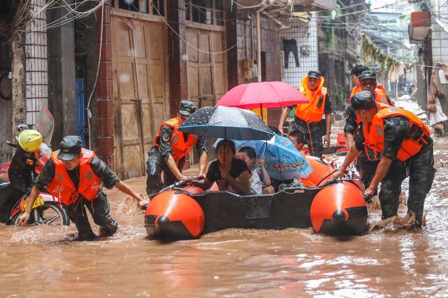 This photo taken on 16 July 2020 shows China's paramilitary police officers evacuating residents at a flooded area due to heavy rains in China's southwestern Chongqing. (STR/AFP)