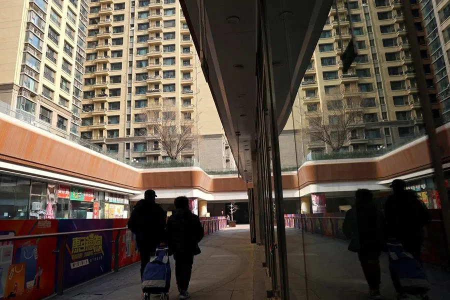 People walk past residential buildings next to the Evergrande City Plaza, after a court ordered the liquidation of property developer China Evergrande Group, in Beijing, China, on 29 January 2024.