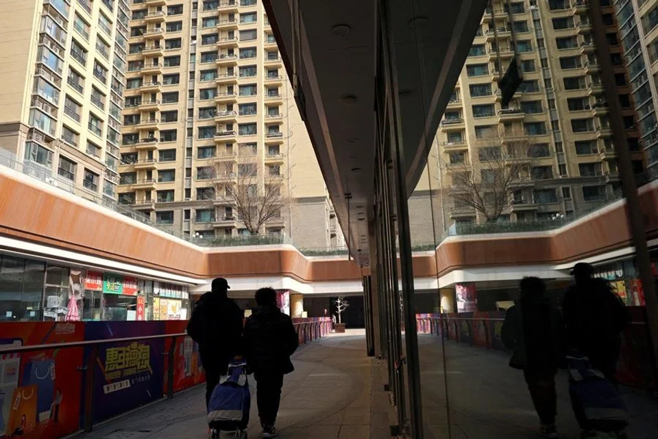 People walk past residential buildings next to the Evergrande City Plaza, after a court ordered the liquidation of property developer China Evergrande Group, in Beijing, China, on 29 January 2024. (Florence Lo/Reuters)