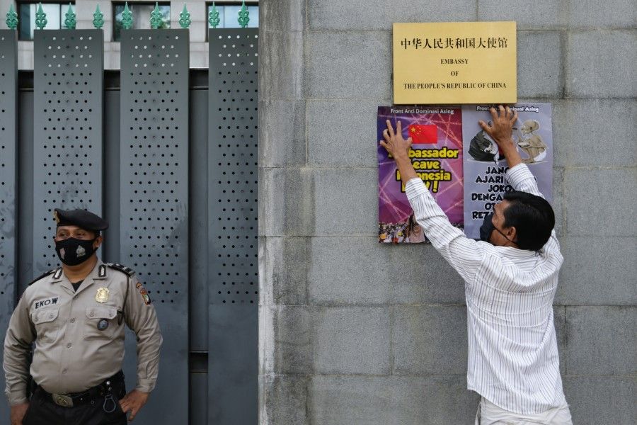 A protester sticks posters outside the Chinese embassy following reports that China has encroached on Indonesia's maritime area in the South China Sea, in Jakarta, Indonesia, 8 December 2021. (Ajeng Dinar Ulfiana/Reuters)