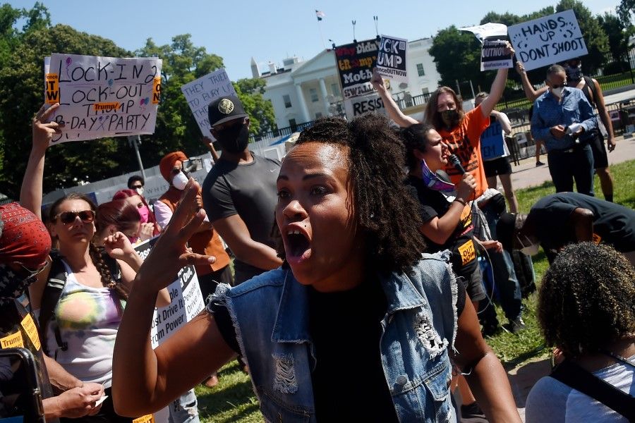 Protesters hold placards and chant slogans in Lafayette Park, across from the White House to protest against police brutality and US President Donald Trump's 74th birthday on 14 June 2020 in Washington, DC. The latest protests come as lawmakers are debating how to reform a judicial system seen by critics as stacked against poor and minority citizens and which has proved stubbornly resistant to change. (Olivier Douliery/AFP)