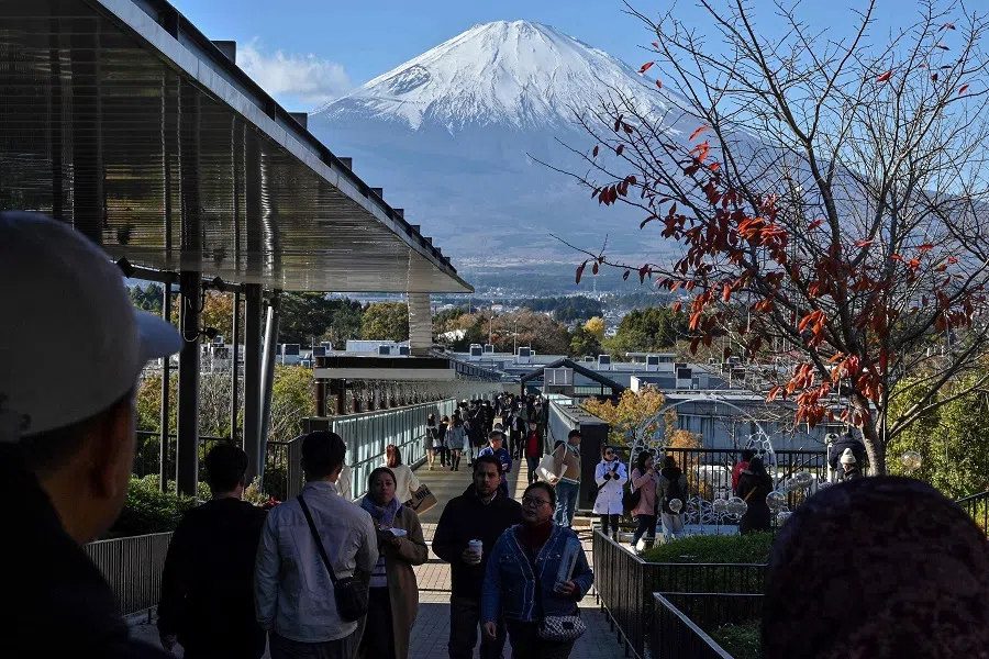 This photo taken on 28 November 2024 shows Mount Fuji pictured in the background as people walk around a popular outlet shopping centre in the city of Gotemba, Shizuoka prefecture, some 100 km southwest of Tokyo. (Richard A. Brooks/AFP)