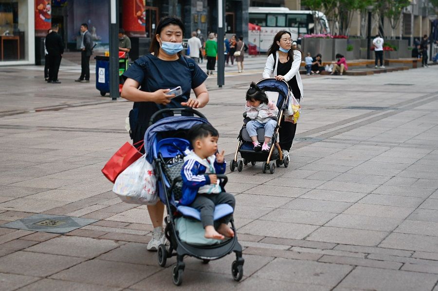 Two women push strollers along a business street in Beijing, China, on 31 May 2021. (Wang Zhao/AFP)