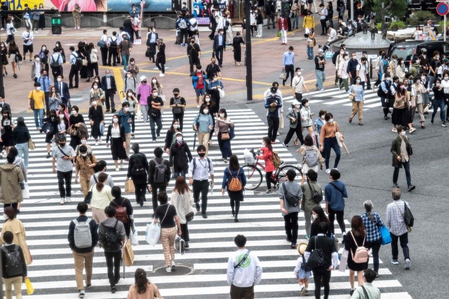 People cross a street in Tokyo on 20 May 2021. (Charly Triballeau/AFP)