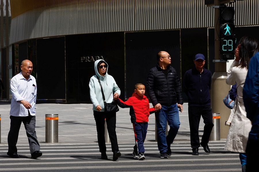 People walk on a street in Beijing, China, 11 April 2023. (Tingshu Wang/Reuters)