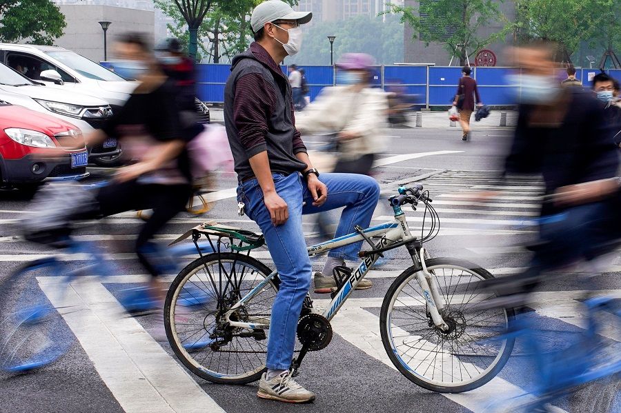 People wearing protective face masks ride bicycles on a street in Wuhan, China, on 14 May 2020. (Aly Song/Reuters)