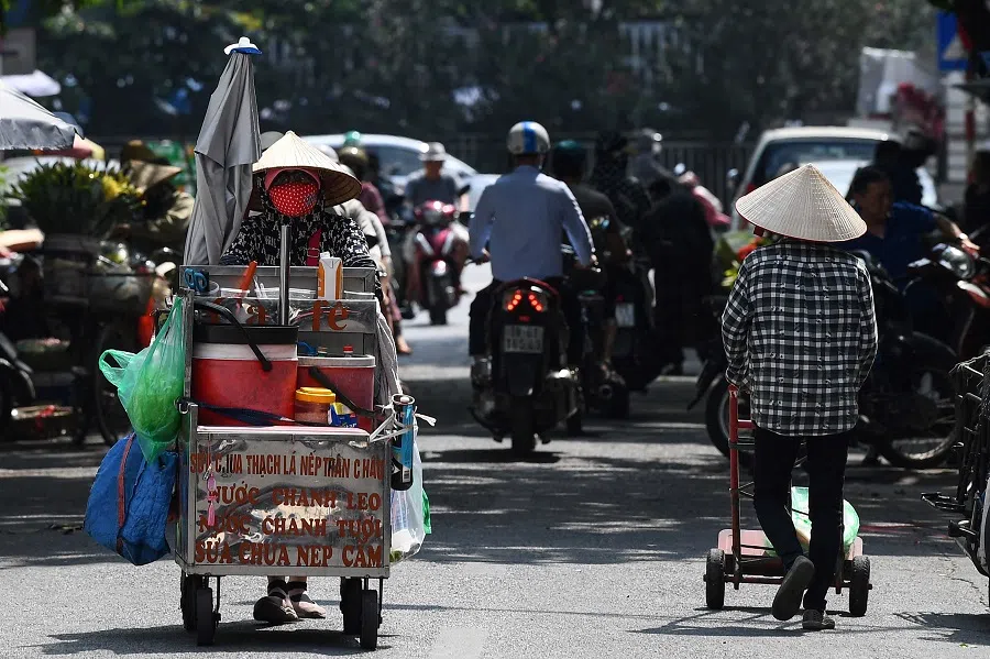 A street vendor (left) pushes her trolley to sell coffee and soft drinks in Hanoi, Vietnam on 1 June 2023. (Nhac Nguyen/AFP)