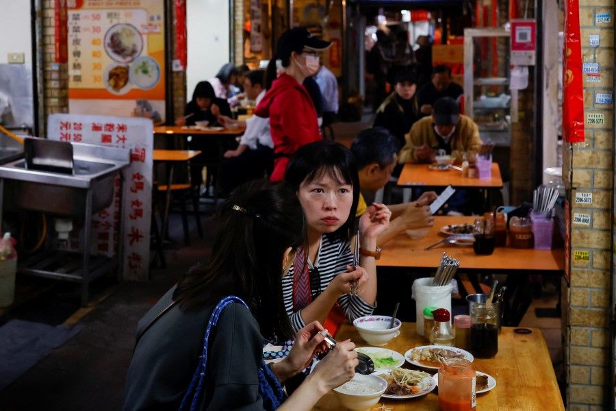 People eat lunch inside a market in Taipei, Taiwan, 7 March 2023. (Ann Wang/Reuters)
