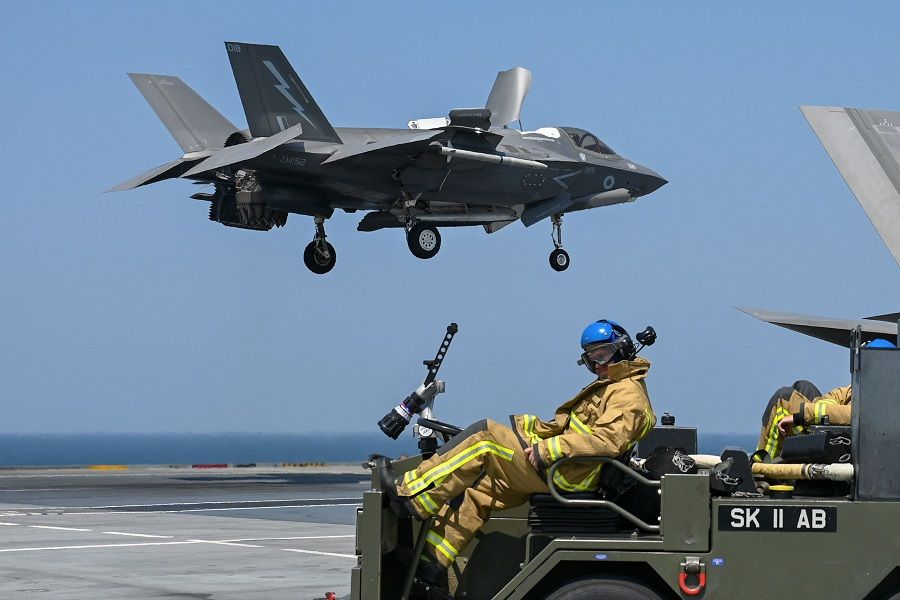 A British serviceman sits on a vehicle as the F-35B fighter jet prepares to land on the flight deck of UK Carrier Strike Group's HMS Queen Elizabeth in the Arabian Sea, off Mumbai's coast on 21 October 2021. (Punit Paranjpe/AFP)
