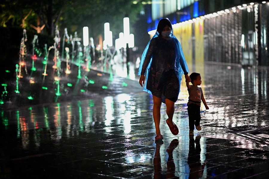 A woman and a child walk past a mall as it rains in Beijing, China, on 23 August 2021. (Noel Celis/AFP)
