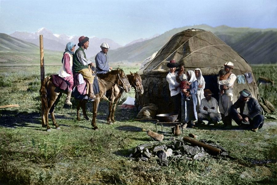 Uzbekistan, Central Asia, early 20th century. A Mongolian yurt stands amid the wide grasslands, as people gather in front of the yurt. A fire for cooking has gone out, and guests are getting on their horses to leave as the host family comes out to see them off. The men on horseback are wearing long robes with slits on the side, with black sheepskin hats. Nomadic men like wearing clothes that are convenient for riding and keeping warm.