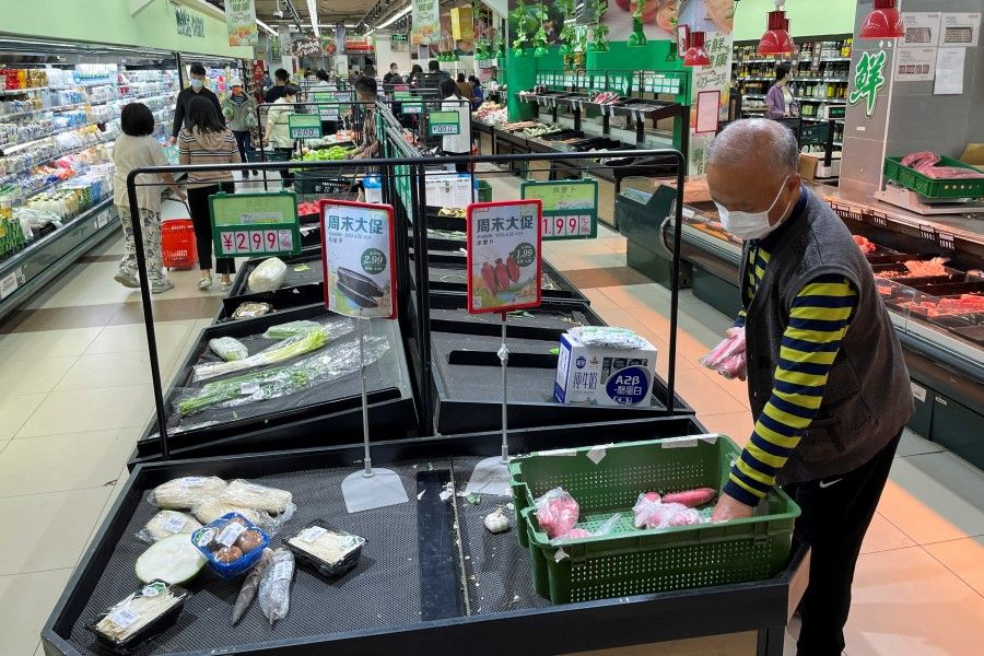 A customer wearing a face mask shops next to near-empty shelves at a supermarket in Chaoyang district of Beijing, China, 24 April 2022. (Carlos Garcia Rawlins/Reuters)