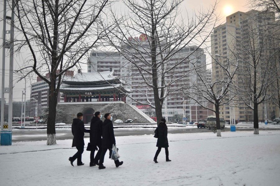 This photo taken on 3 December 2022 shows pedestrians walking after the first snow fall of the year in the Pothonggang District of Pyongyang. (Kim Won Jin/AFP)