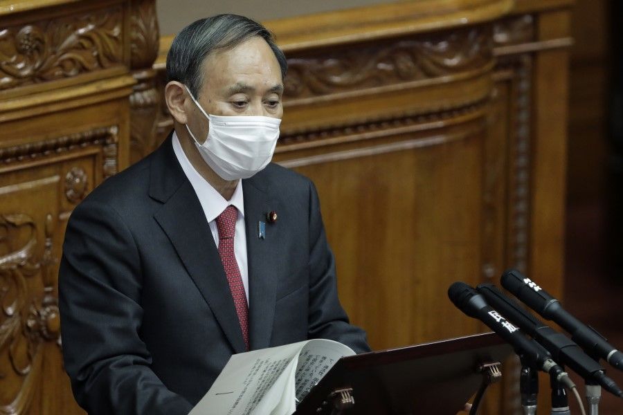 Yoshihide Suga, Japan's prime minister, wears a protective face mask as he speaks during a plenary session at the upper house of parliament in Tokyo, Japan, 30 November 2020. (Kiyoshi Ota/Bloomberg)