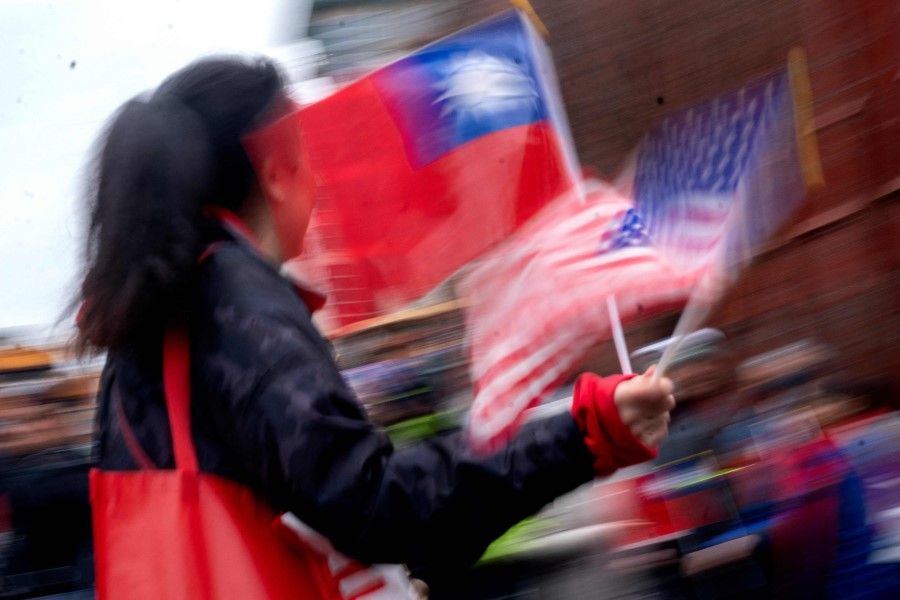 A participant waves flags from the US and Taiwan during the Lunar New Year Parade in the Chinatown neighbourhood of Washington, DC, on 22 January 2023. (Stefani Reynolds/AFP)