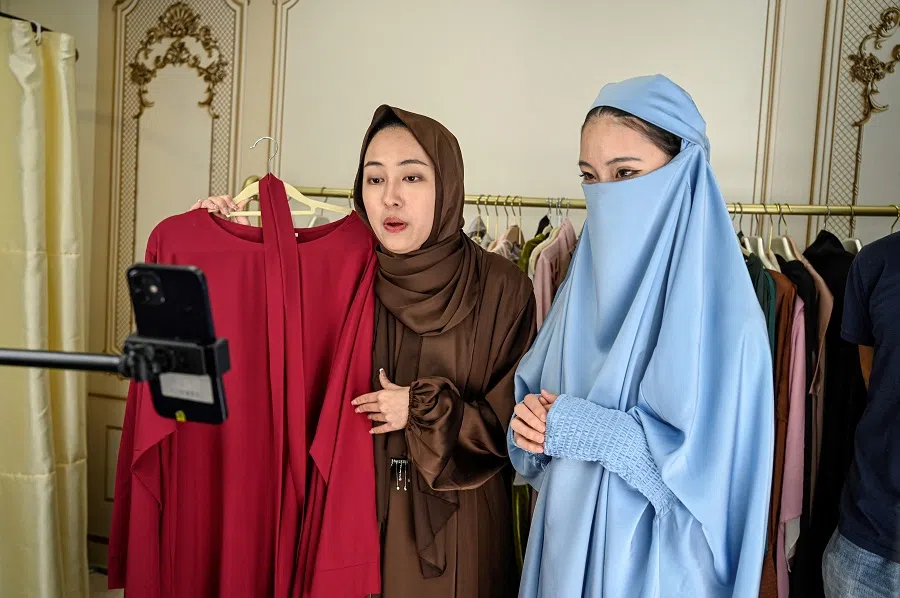 The photo taken on 2 April 2024 shows students wearing abaya gowns and hijabs practising live streaming on TikTok at Mede Education Technology’s e-commerce school in Guangzhou, China. Donning hijabs and floor-length abaya gowns over shorts and tank tops, Chinese students at an e-commerce school perform into a smartphone camera as they learn how to sell the clothes to overseas TikTok users. (Jade Gao/AFP)