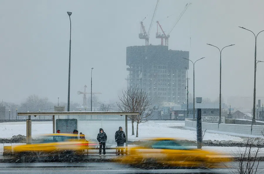 People gather at a bus stop near a construction site in Moscow, Russia, on 13 December 2024. (Maxim Shemetov/Reuters)
