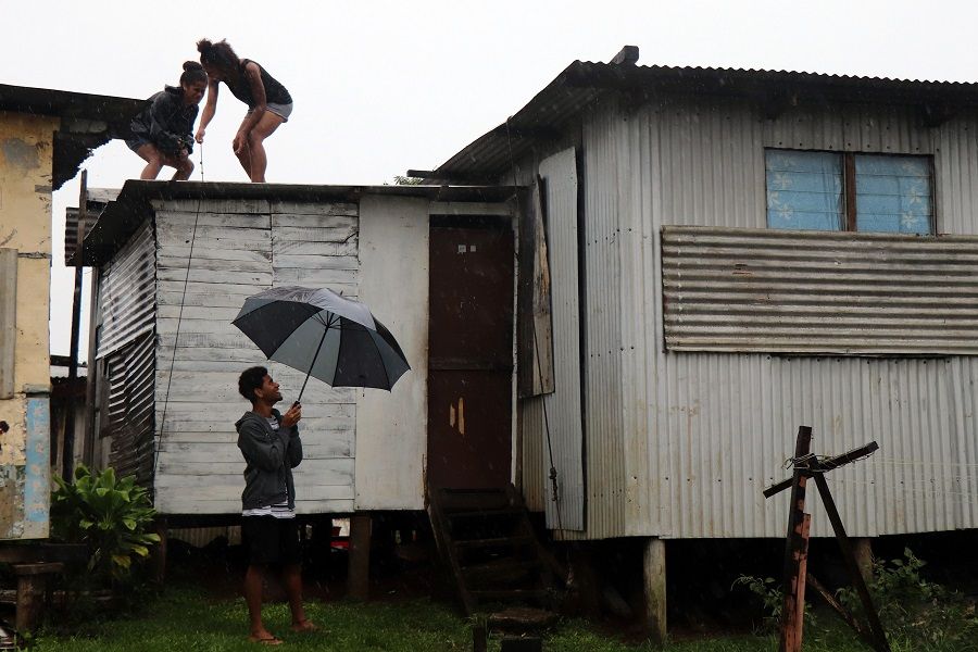 This picture taken on 17 December 2020 shows residents checking the rooftops of their houses as gusty winds build up ahead of cyclone Yasa in Fiji's capital city of Suva. (Lice Movono/AFP)