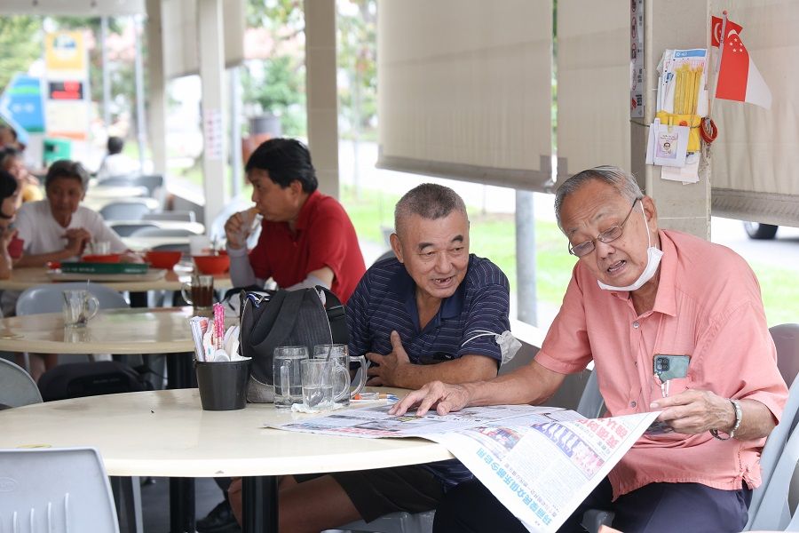 People having a chat over a newspaper article at a neighbourhood coffeeshop in Singapore. (SPH Media)
