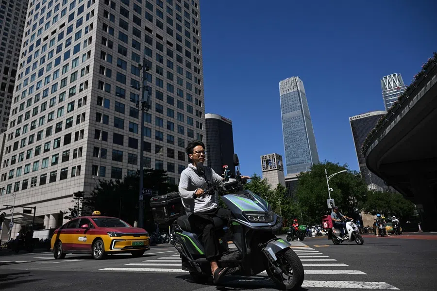 A man rides a scooter in the central business district of Beijing, China, on 8 September 2025. (Jade Gao/AFP)
