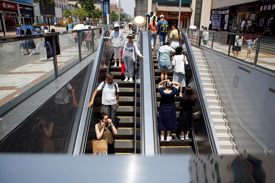 People ride elevators at a shopping street in Beijing, China, on 16 June 2023. (Florence Lo/Reuters)