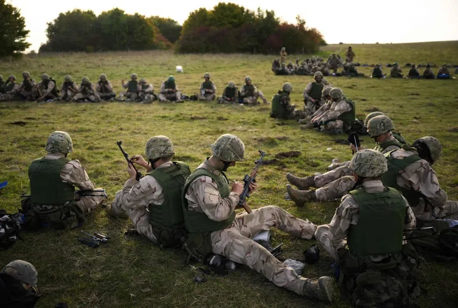 Ukrainian recruits lubricate their AK-47 assault rifles during a five-week combat training course with the UK armed forces near Durrington in southern England on 11 October 2022. (Daniel Leal/AFP)