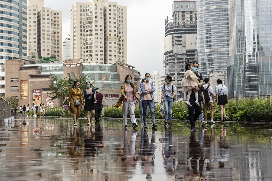 Pedestrians wearing protective masks walk along a promenade near a shopping mall in Shanghai, China, on 14 August 2021. (Qilai Shen/Bloomberg)