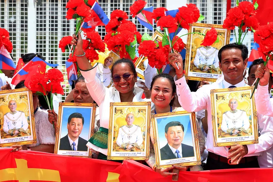 This pool photo taken and released on 17 April 2025 by Agence Kampuchea Presse (AKP) shows people holding portrait photos of China’s President Xi Jinping and Cambodia’s King Norodom Sihamoni during a welcome ceremony at Phnom Penh International Airport, Cambodia. (Pool/AFP)