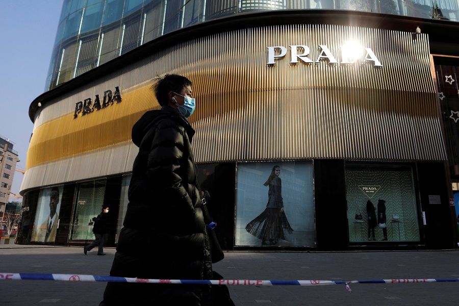 A man wearing a face mask walks past a store of Italian luxury brand Prada on a shopping street in Beijing, China, 20 January 2021. (Tingshu Wang/Reuters)