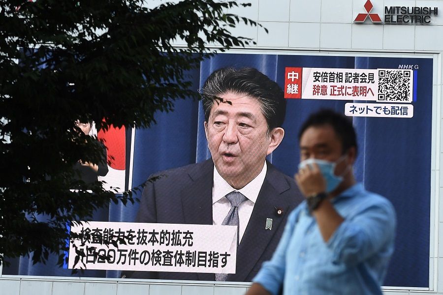 A man walks past a large screen showing Japanese Prime Minister Shinzo Abe's live press conference in Tokyo on 28 August 2020. (Philip Fong/AFP)