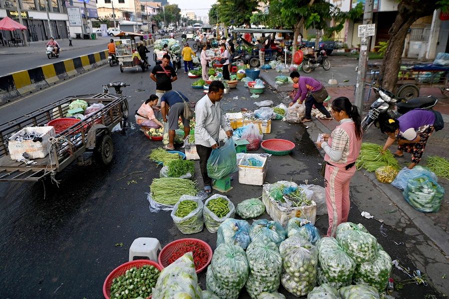 A woman buys vegetables along a street in Phnom Penh, Cambodia, on 8 March 2022. (Tang Chhin Sothy/AFP)