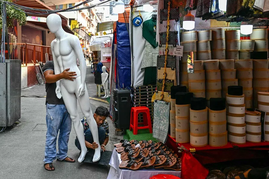 Two men prepare a mannequin at a bazaar selling clothing in Kuala Lumpur, Malaysia, on 7 March 2025. (Mohd Rasfan/AFP)