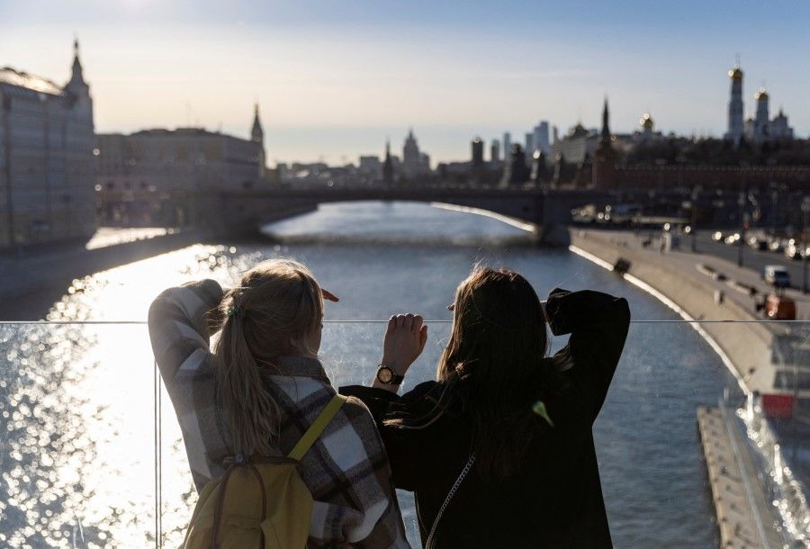 Young women look at panorama of Moskva River and Kremlin at a viewpoint in central Moscow, Russia, 22 March 2022. (Maxim Shemetov/Reuters)