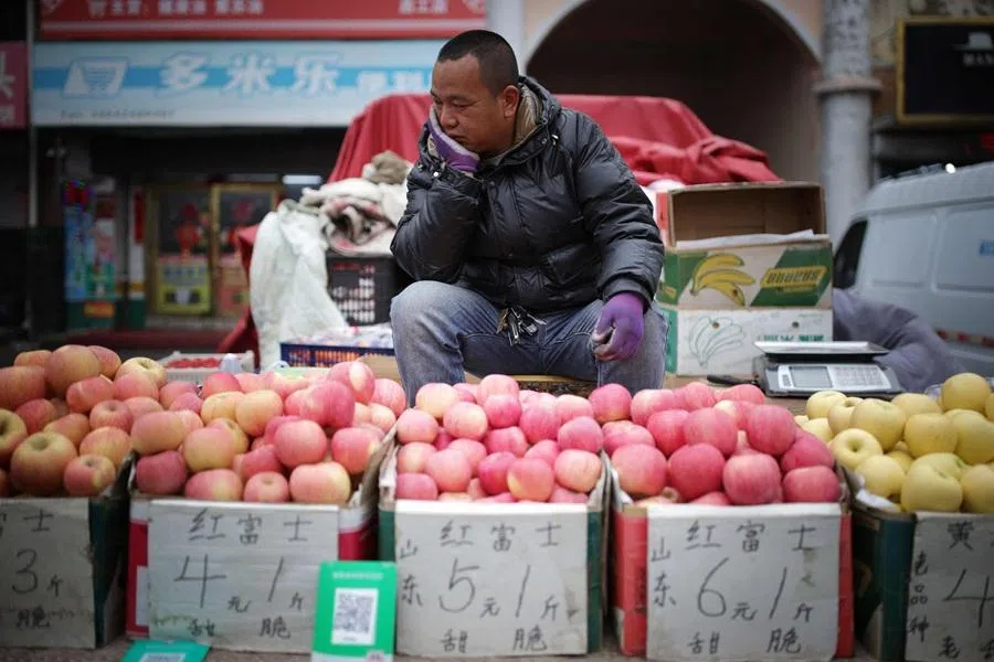 A fruit vendor waits for customers at a market in Shenyang, in China's northeast Liaoning province on 10 April 2026. (AFP)