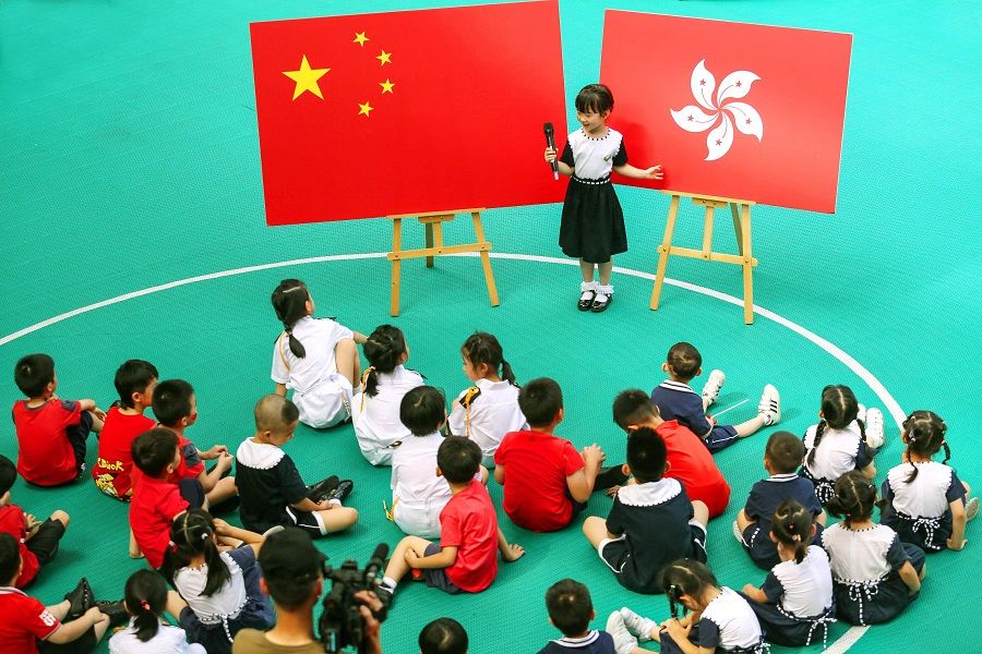 Over in Shenzhen, a child introduces the Hong Kong flag to her classmates at a kindergarten, ahead of Hong Kong's handover anniversary on 1 July. (STR/AFP)