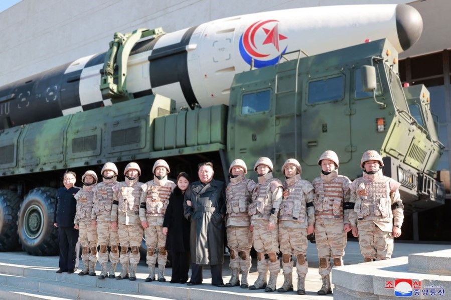 This undated picture released from North Korea's official Korean Central News Agency (KCNA) on 27 November 2022 shows North Korea's leader Kim Jong Un (centre right) and his daughter (centre left) posing with soldiers who contributed to the test-firing of the new intercontinental ballistic missile (ICBM), at an unknown location in North Korea. (KCNA via KNS/AFP)