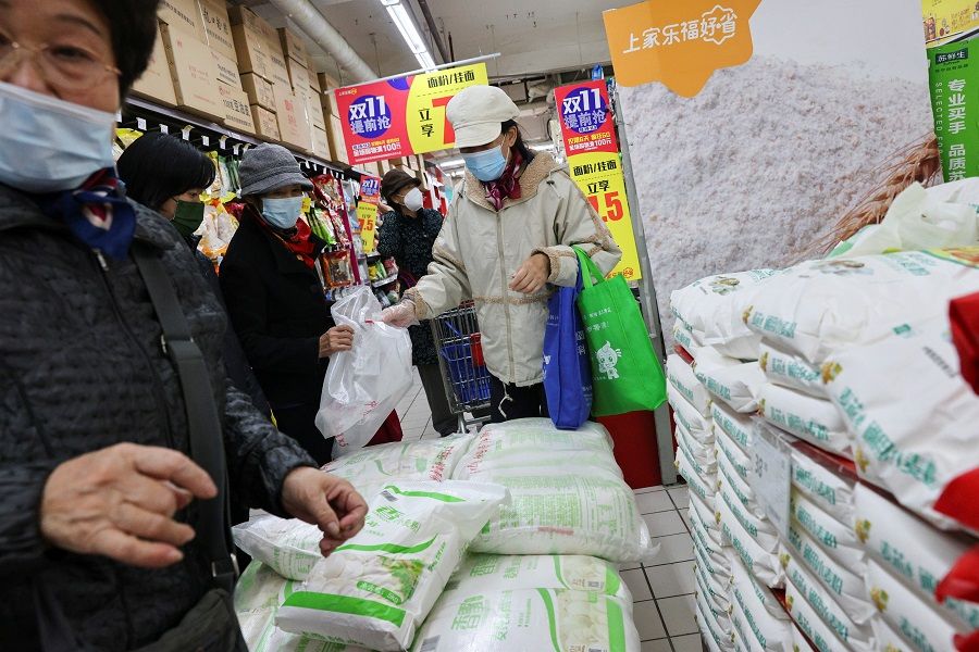 People buy bags of rice at a supermarket in Beijing, China, 3 November 2021. (Thomas Peter/Reuters)