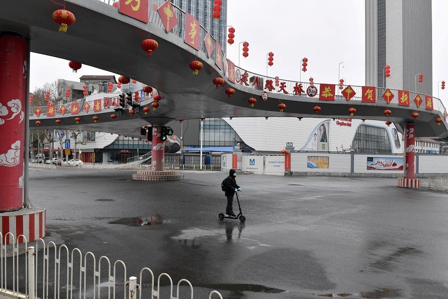 A man wearing a face mask rides a kick scooter through an intersection in Wuhan, the epicentre of the Covid-19 pandemic, in Hubei province, China, 3 March 2020. (Stringer/Reuters)