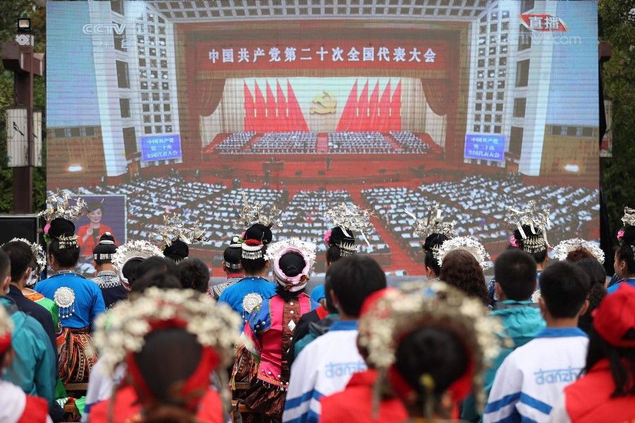 Ethnic minority members watch the opening session of the 20th Chinese Communist Party Congress on a screen in Danzhai, Guizhou province, China, on 16 October 2022. (AFP)
