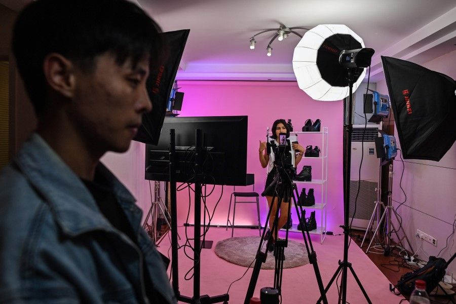 This photo taken early on October 23, 2020 shows Silvia Rivera (in background) attending a livestreaming event from a studio in Shanghai to offer products on an Aliexpress channel in Spain. By some estimates, livestream shopping is a near US$70 billion industry inside China. (Hector Retamal/AFP)