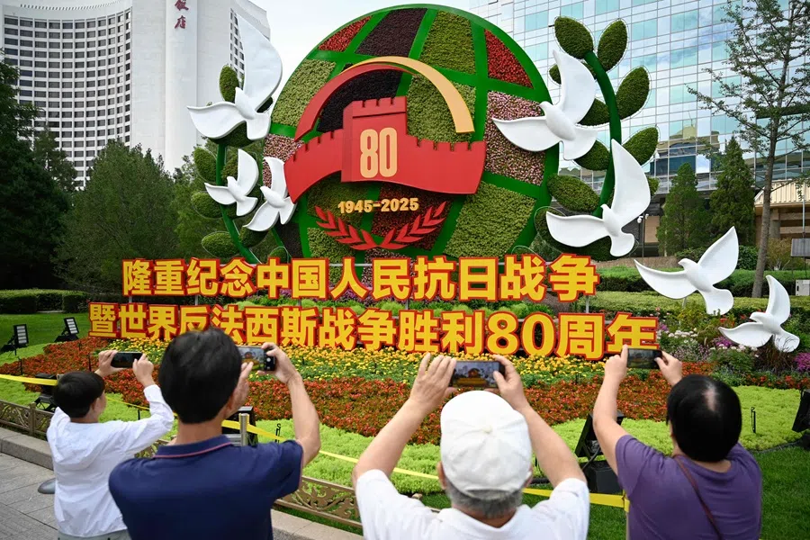 People take pictures of a flower installation commemorating the 80th anniversary of the victory over Japan and the end of World War II at the National Art Museum of China in Beijing on 28 August 2025.