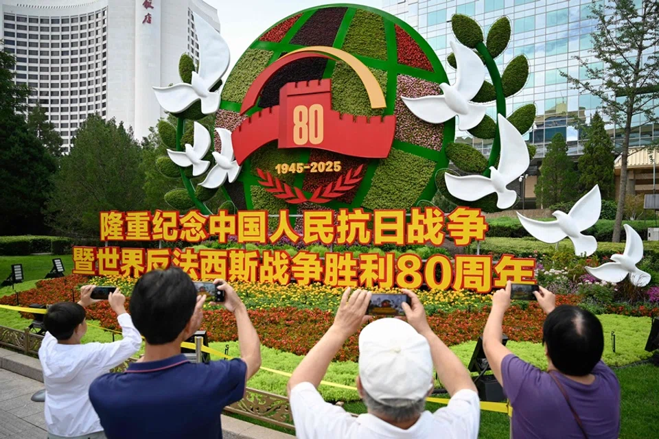 People take pictures of a flower installation commemorating the 80th anniversary of the victory over Japan and the end of World War II at the National Art Museum of China in Beijing on 28 August 2025. (Wang Zhao/AFP)
