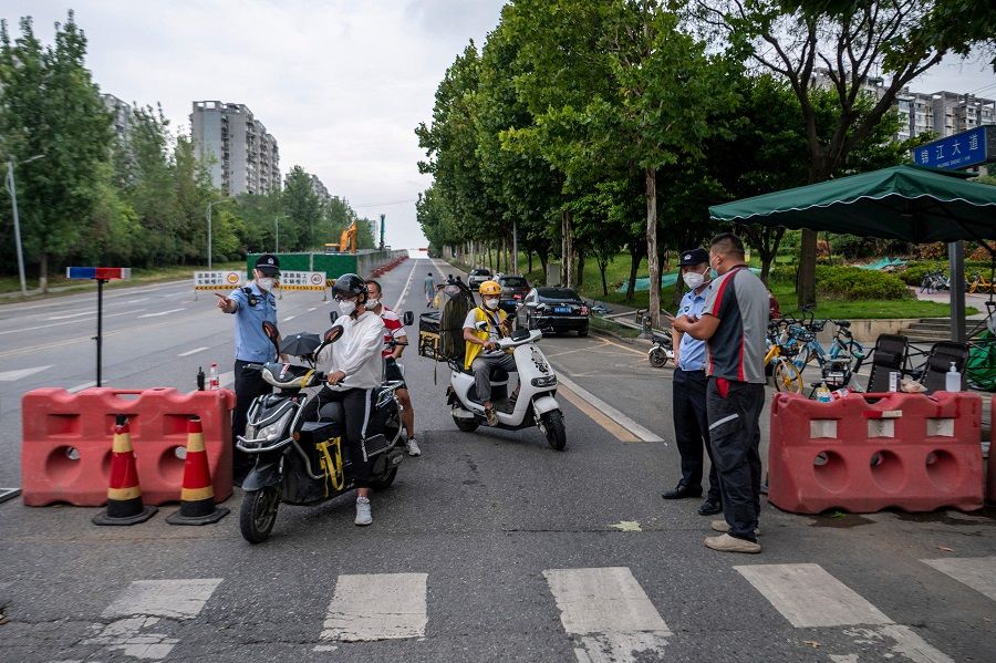 This photo taken on 1 September 2022 shows police officers checking information on a road amid restrictions due to an outbreak of Covid-19 in Chengdu, Sichuan province, China. (CNS/AFP)