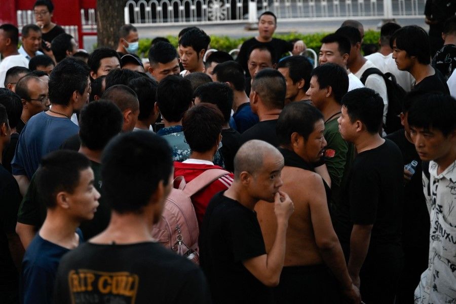 Men gather at a labour market in Beijing on 15 August 2023, where people are hired for temporary jobs at factories and construction sites. (Pedro Pardo/AFP)