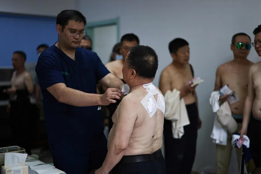 Men line up to receive traditional medicine patches at a traditional Chinese medicine hospital in Shenyang, Liaoning province, China, on 15 July 2024. (AFP)