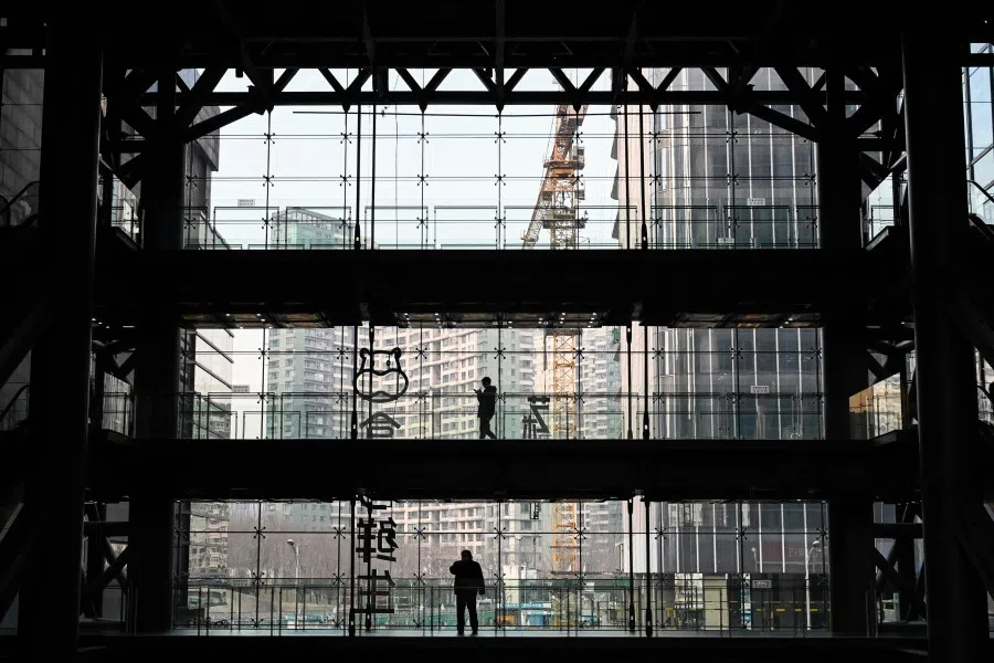 People are silhouetted in an office building in Beijing on 15 December 2021. (Jade Gao/AFP)